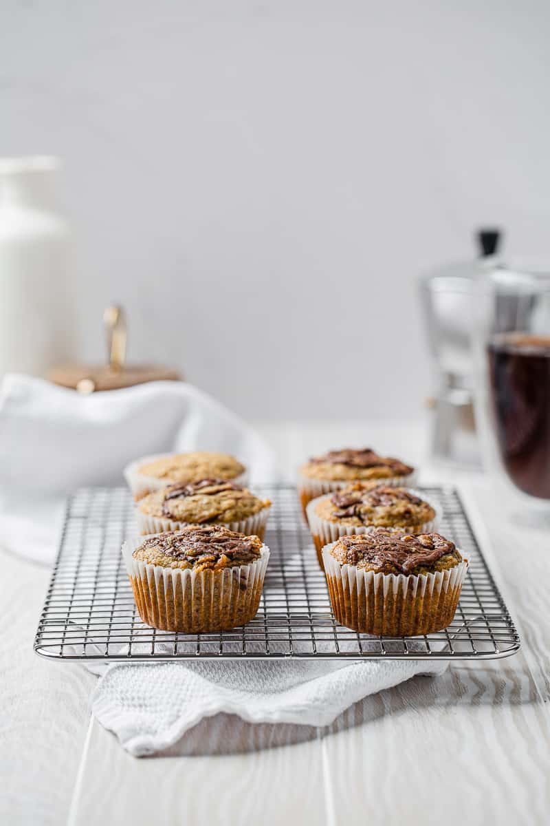 banana nutella muffins on a cooling rack with coffee in the background