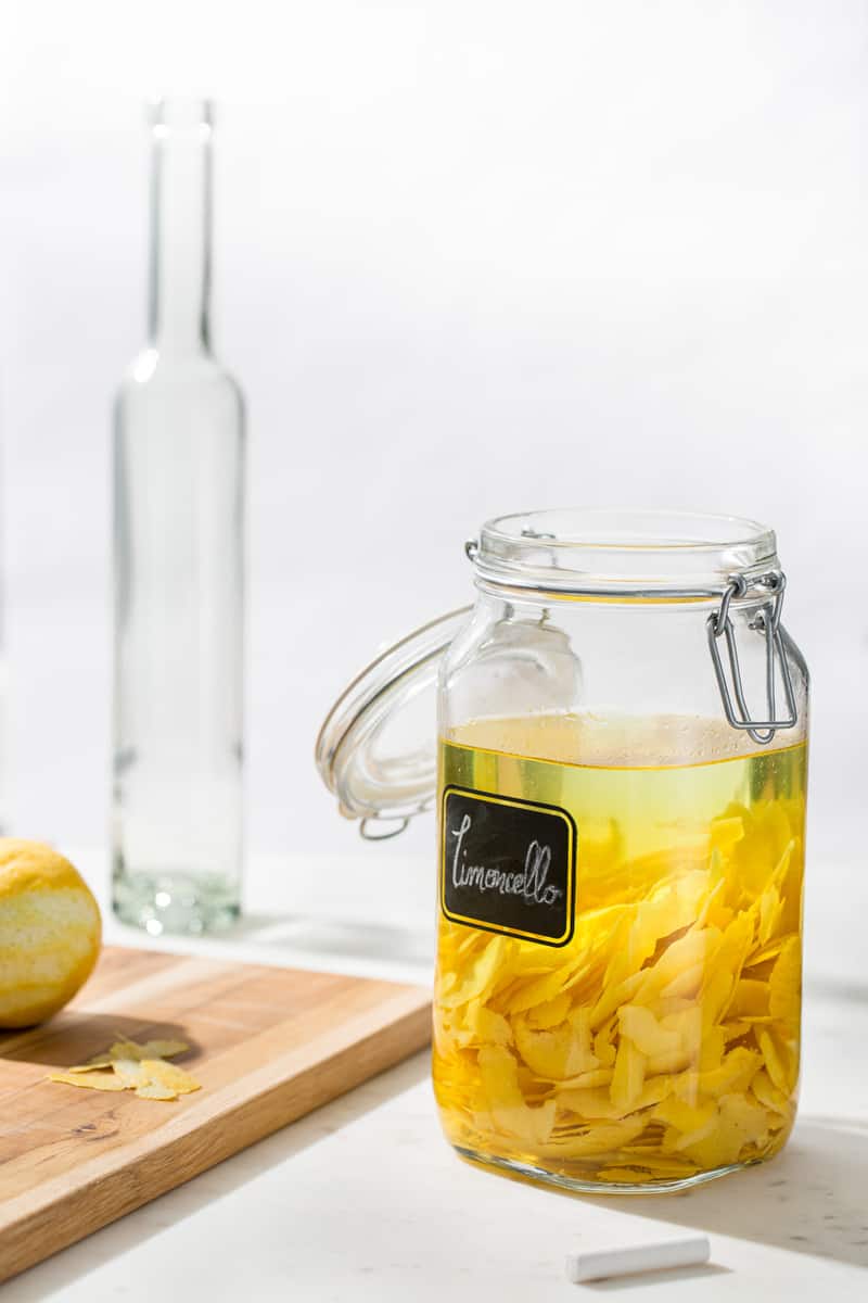 Lemon peels and vodka in container for homemade limoncello
