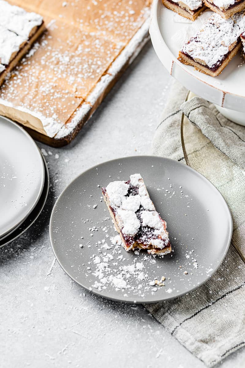 raspberry linzer bar with a bite taken out of it on a plate