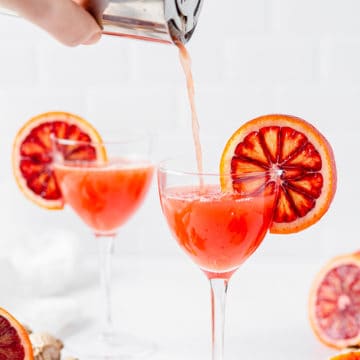 pouring blood orange cocktail into glass