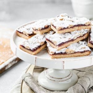 raspberry linzer bars in a pile on a cake plate