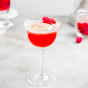 angled view of raspberry mocktail with some raspberries in the background