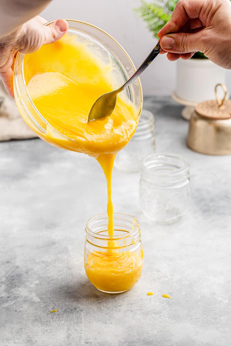 pouring pineapple curd into a mason jar