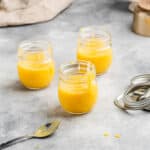three jars of pineapple curd with the tops off to the side