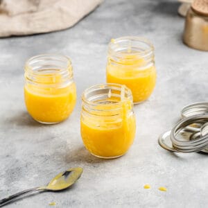 three jars of pineapple curd with the tops off to the side