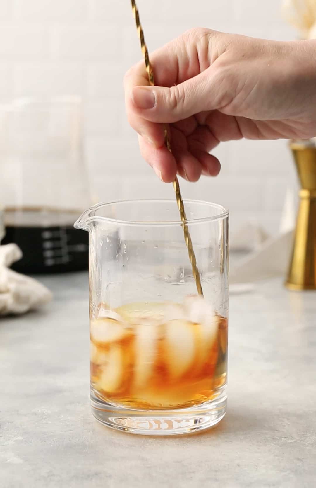 stirring the bourbon and liqueur with ice in a cocktail mixing glass