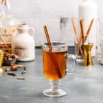 hot apple cider cocktail in front with ingredients in the background