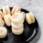 group of macarons with pink and yellow filling on a black plate