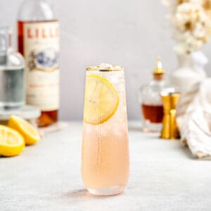 side view of lillet gin cocktail in a stemless champagne glass with gold rim