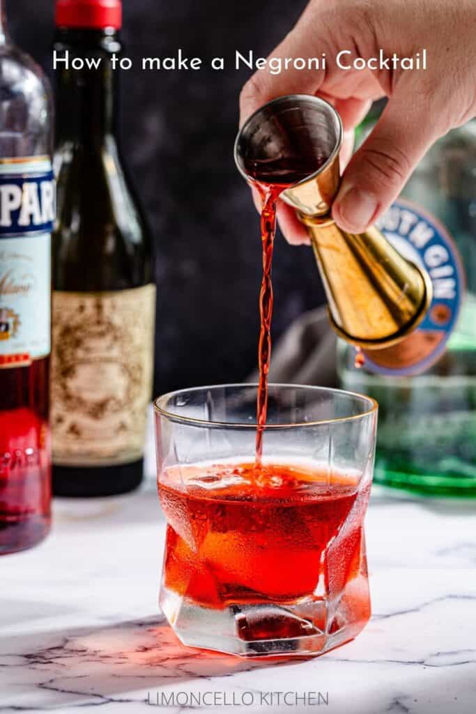 pouring Campari into cocktail glass filled with a red cocktail, with text saying "How to Make a Negroni Cocktail"