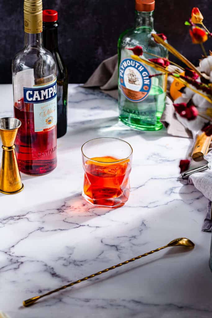 view of finished Negroni cocktail with Campari, vermouth and gin bottles