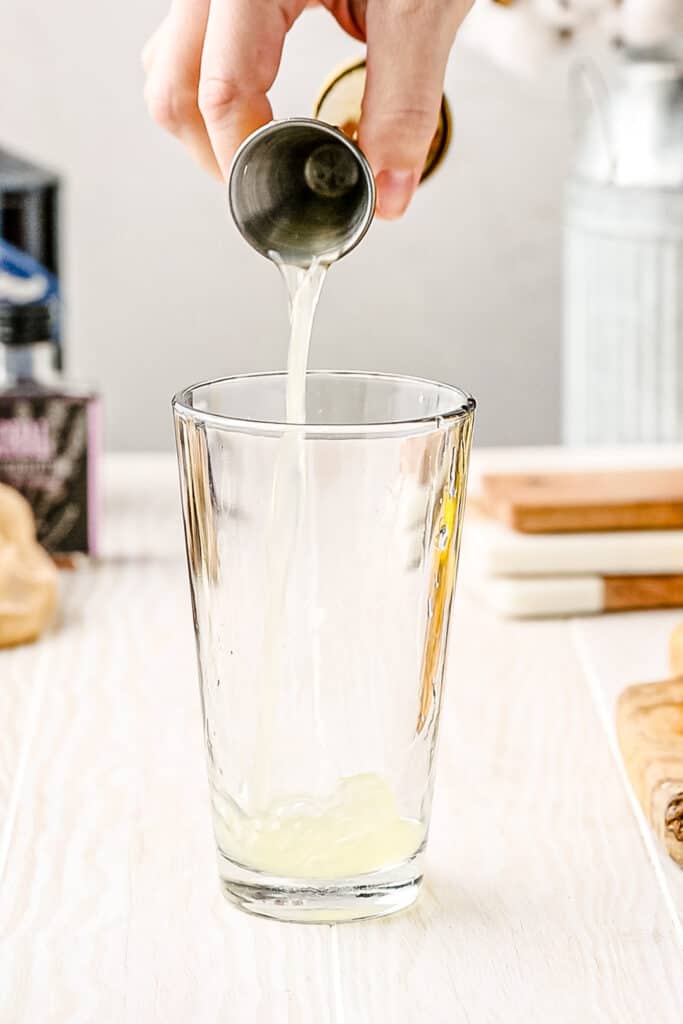 adding fresh lemon juice to cocktail shaker