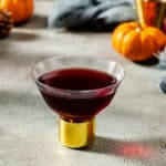 black heart cocktail with mini pumpkins in the backround