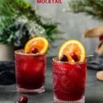 cranberry and orange juice mocktails on a countertop with orange and cranberry garnish