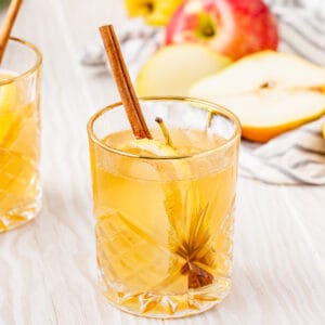 fall sangria with apple cider in a gold rimmed glass with cinnamon stick garnish