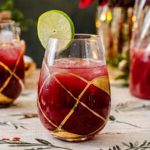 side view of glass filled with christmas morning punch and a lime wheel garnish