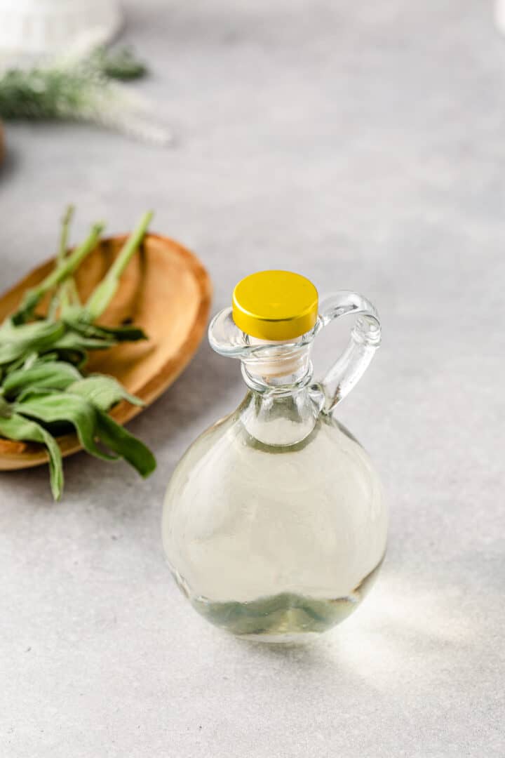 Overhead shot of fresh sage next to a bottle of simple syrup.