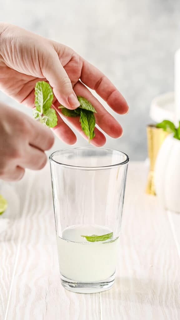 Dropping fresh mint leaves into a cocktail shaker.