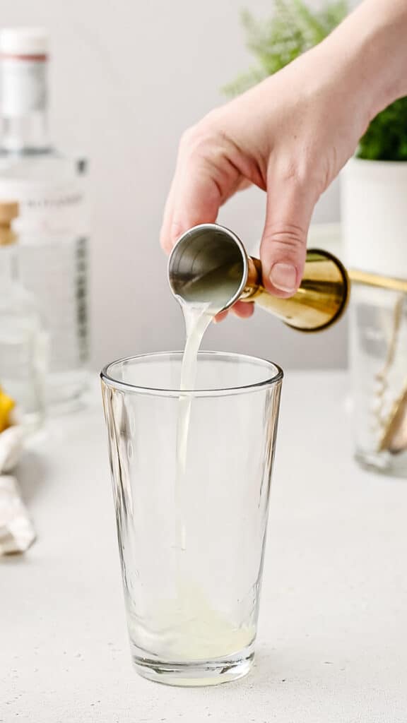 pouring lemon juice into glass cocktail shaker