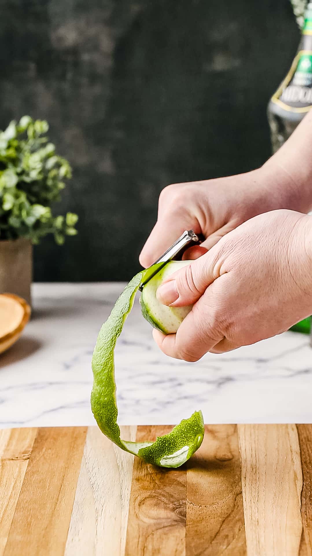 Using a peeler to peel a long strip of lime zest.