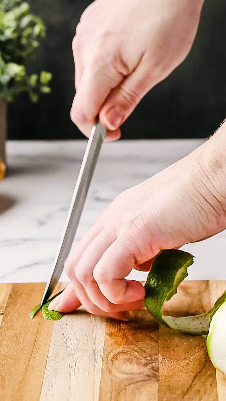 Using a knife to clean up the edges of the peeled lime zest.
