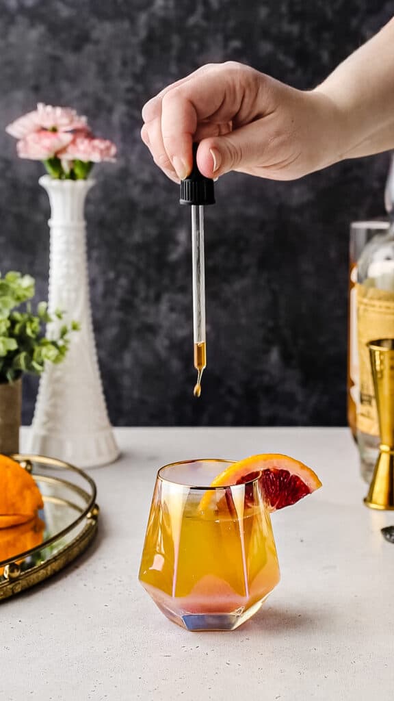 Using a dropper to add bitters to a cocktail.