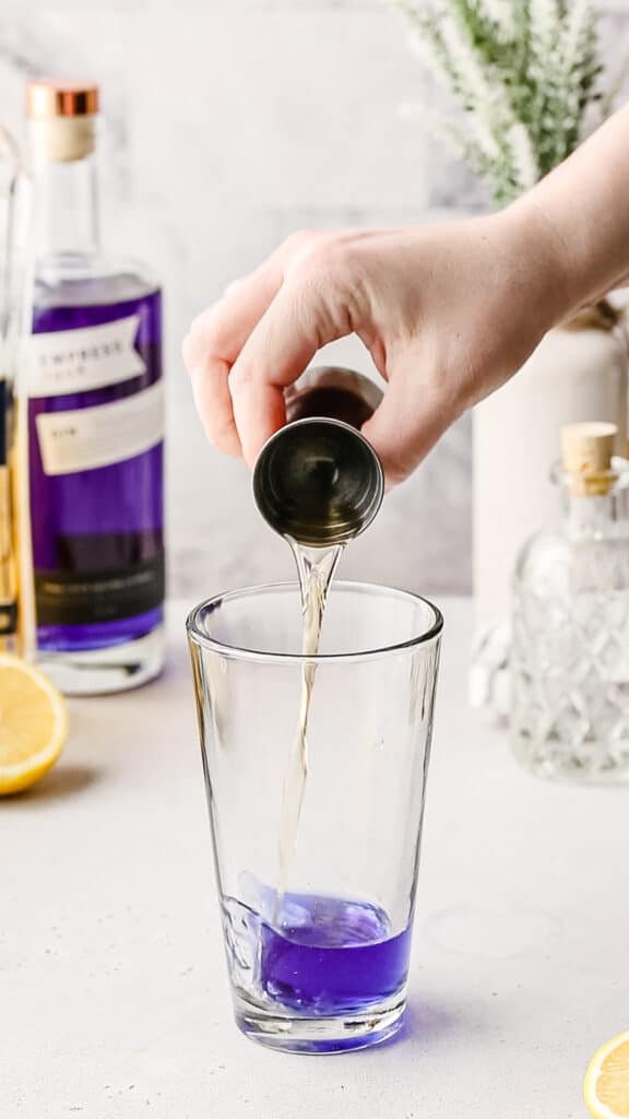 Pouring St Germain liqueur into a cocktail shaker.