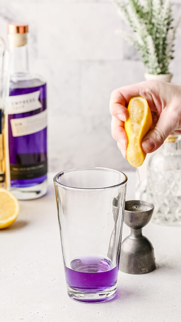 Hand squeezing lemon into a cocktail jigger.