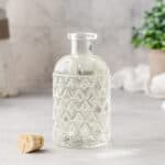Glass bottle filled with simple syrup with a cork next to it.