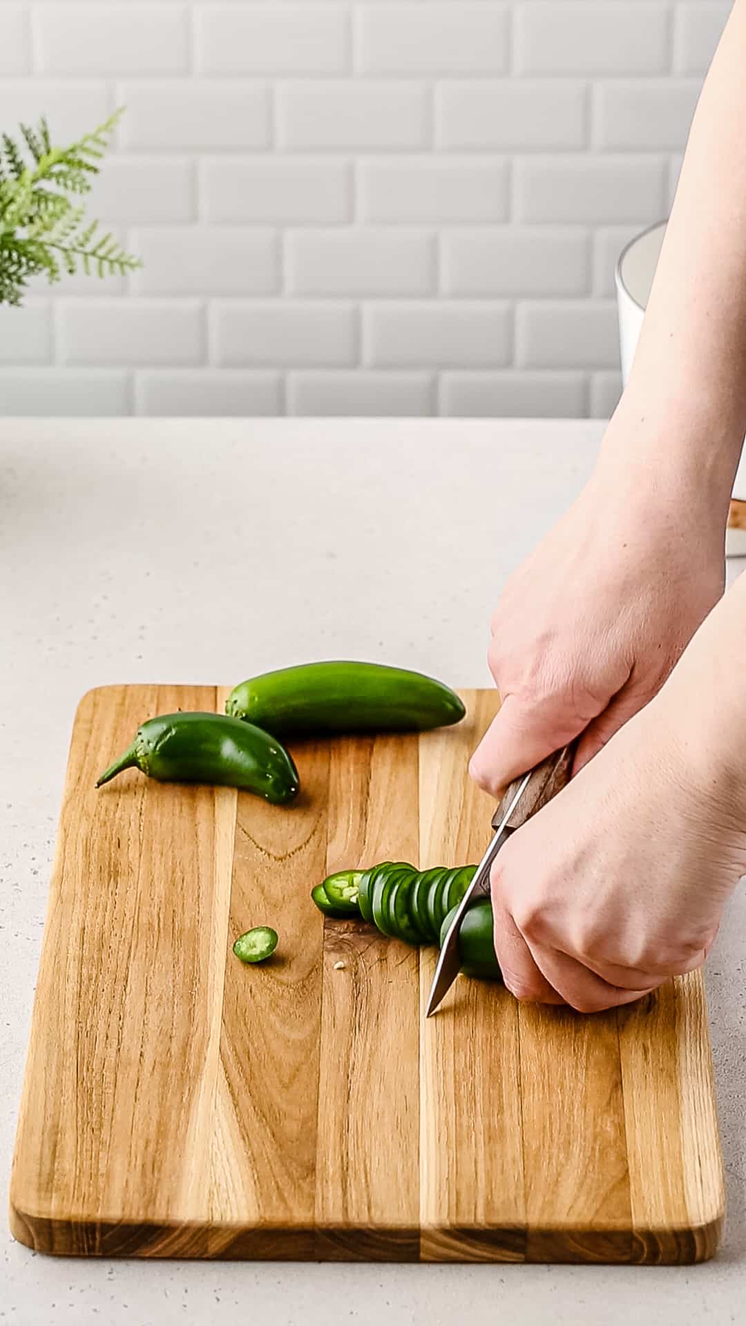 Hands cutting up jalapeno peppers.