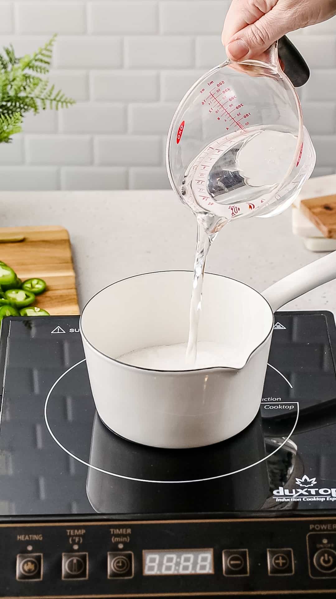 Pouring measured water into a saucepan.