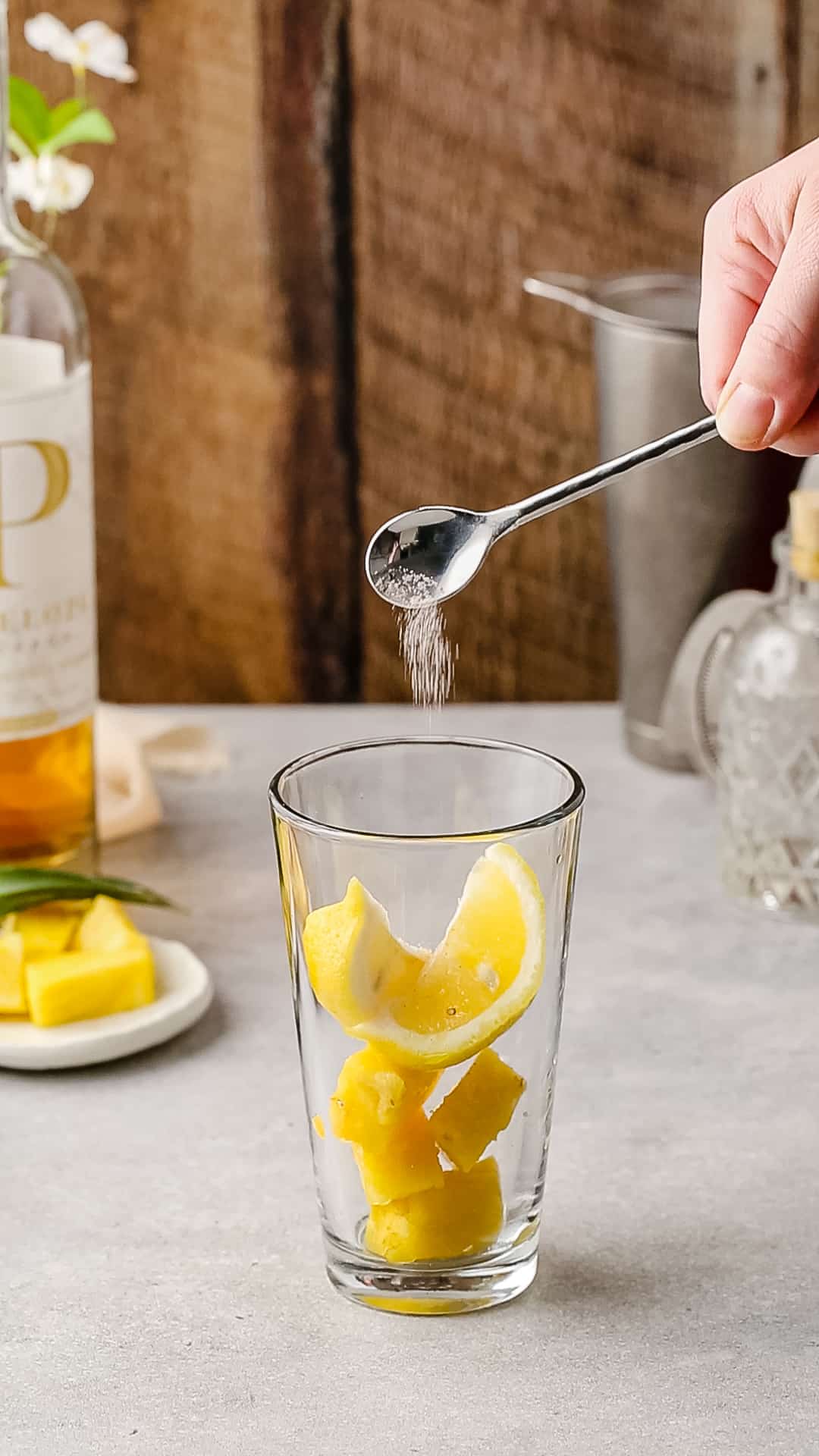 Adding a small amount of salt to the fruit in a cocktail shaker.