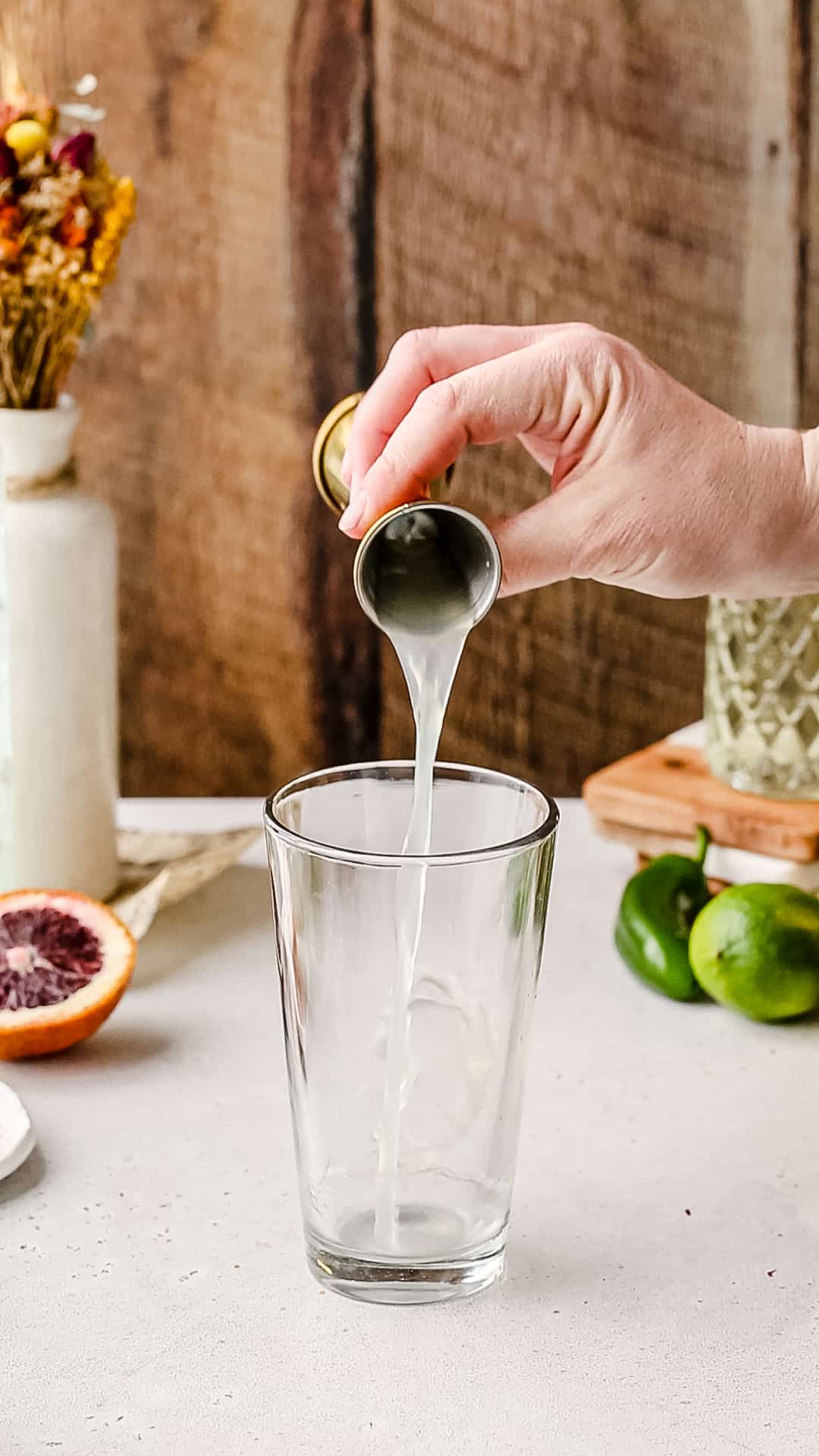 Pouring lime juice into a cocktail shaker.