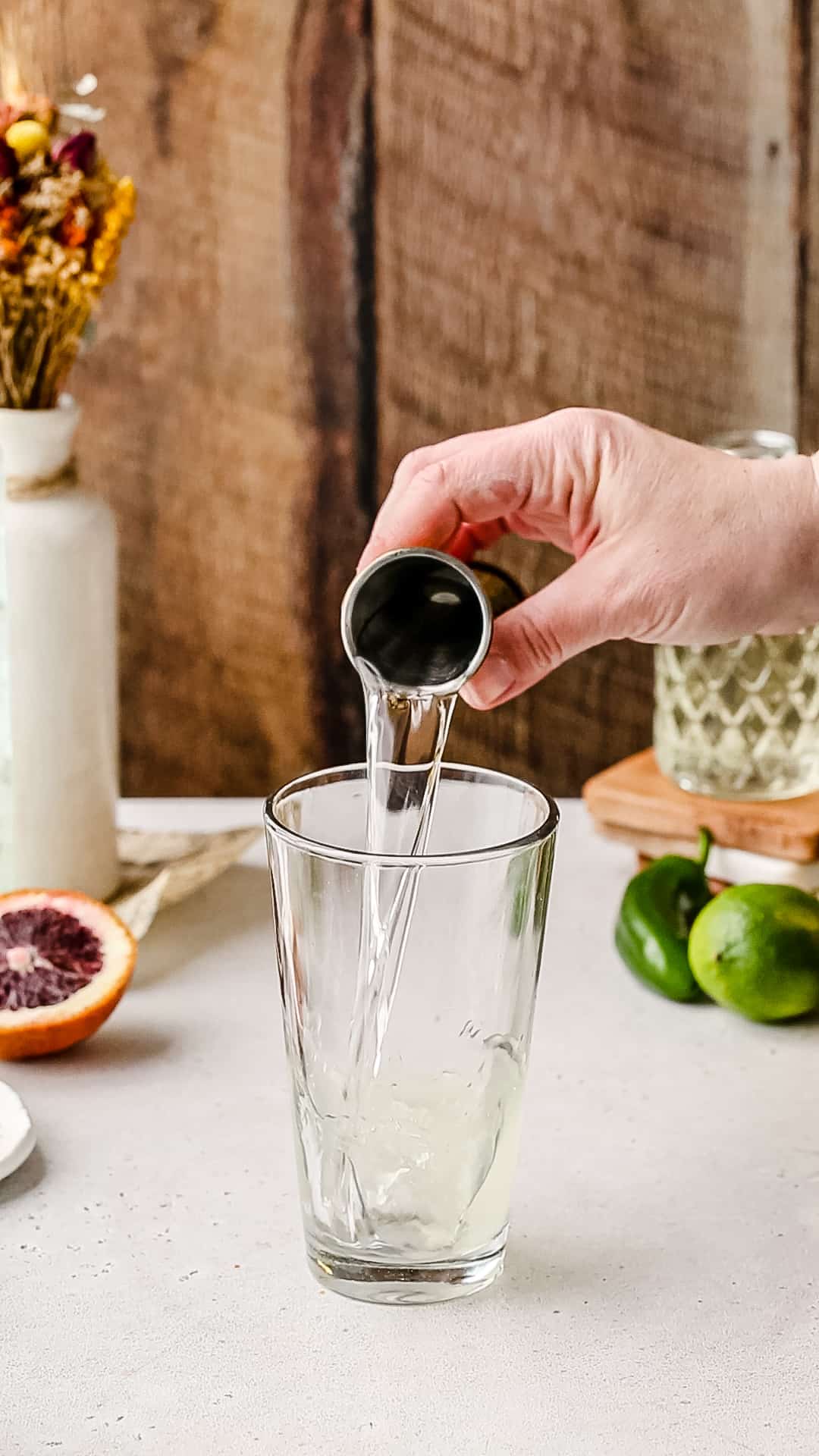 Pouring tequila blanco into a cocktail shaker.
