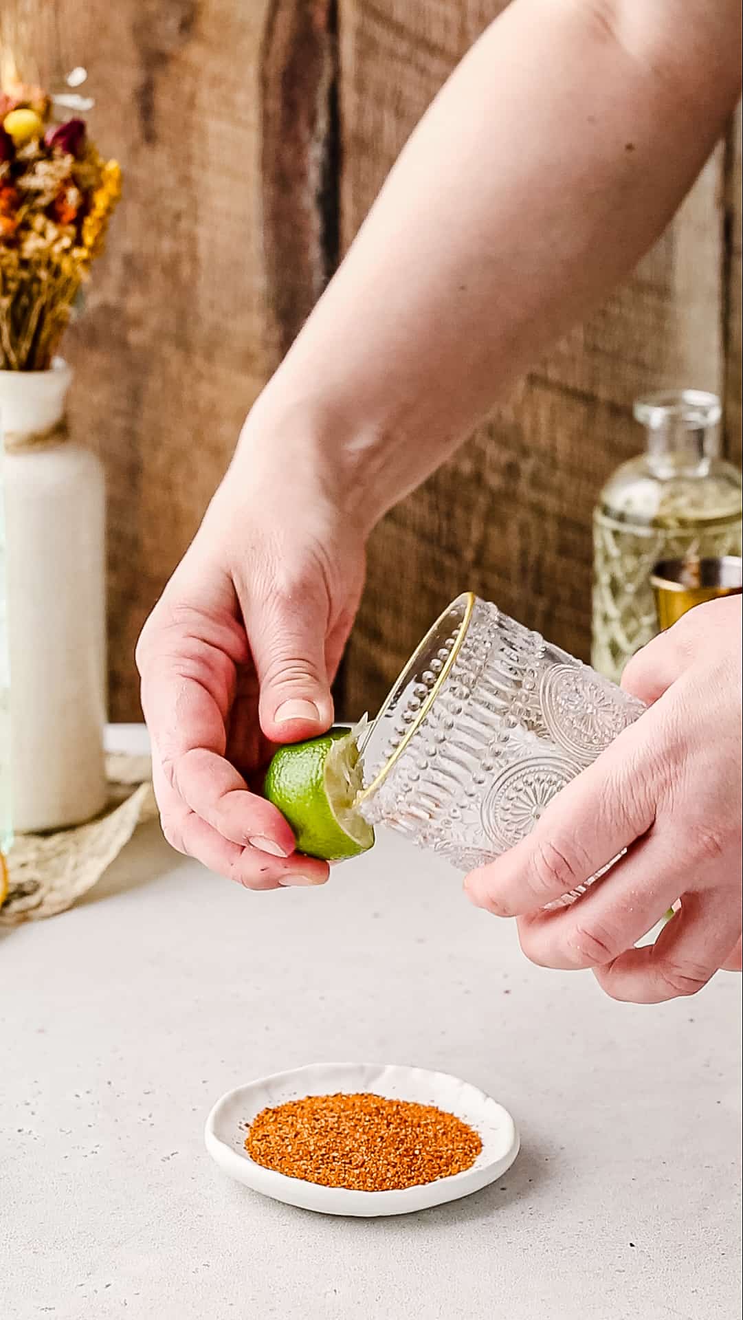 Hand rubbing a cut lime around the rim of a cocktail glass.