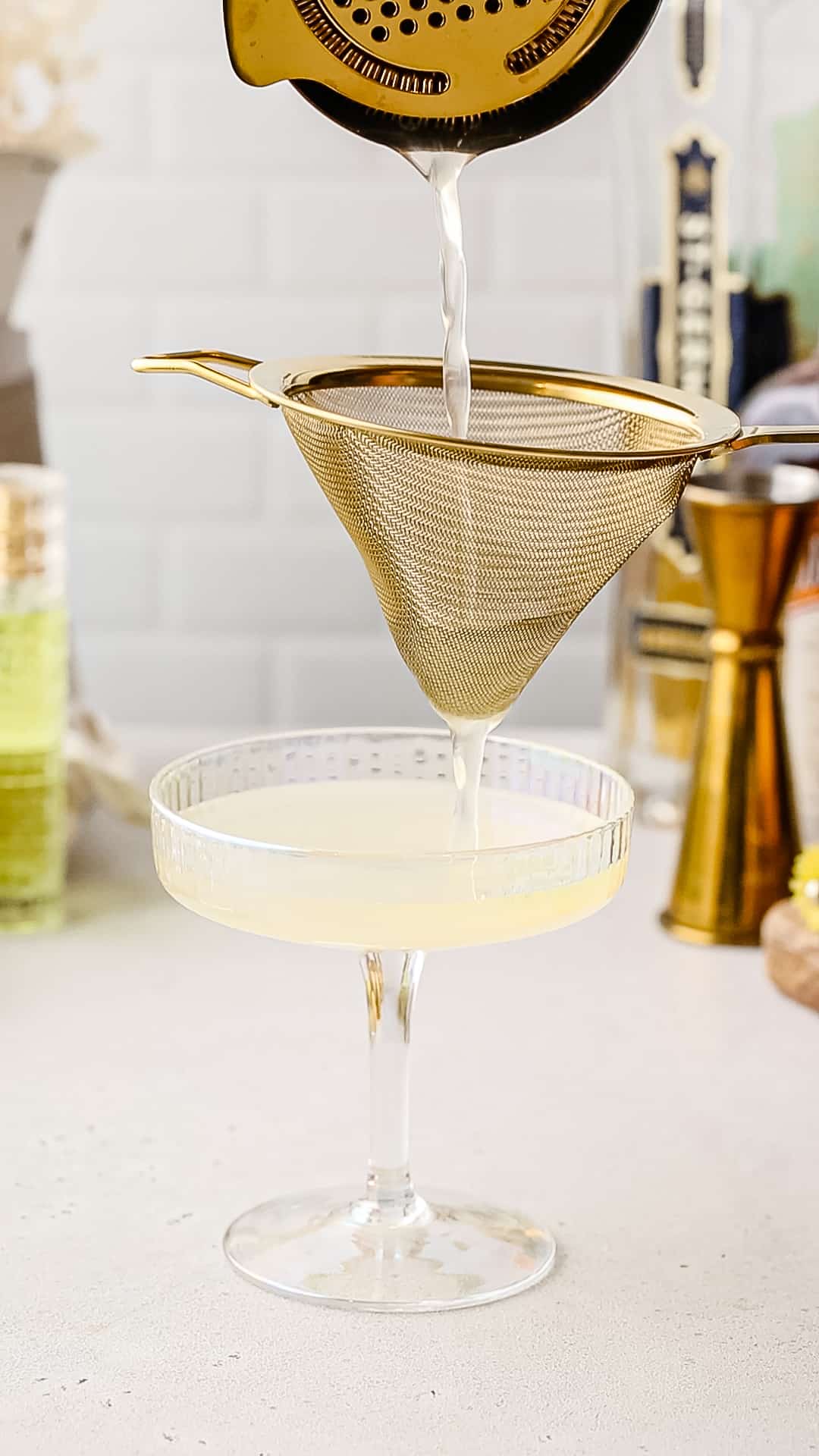 Straining a drink into a coupe cocktail glass.