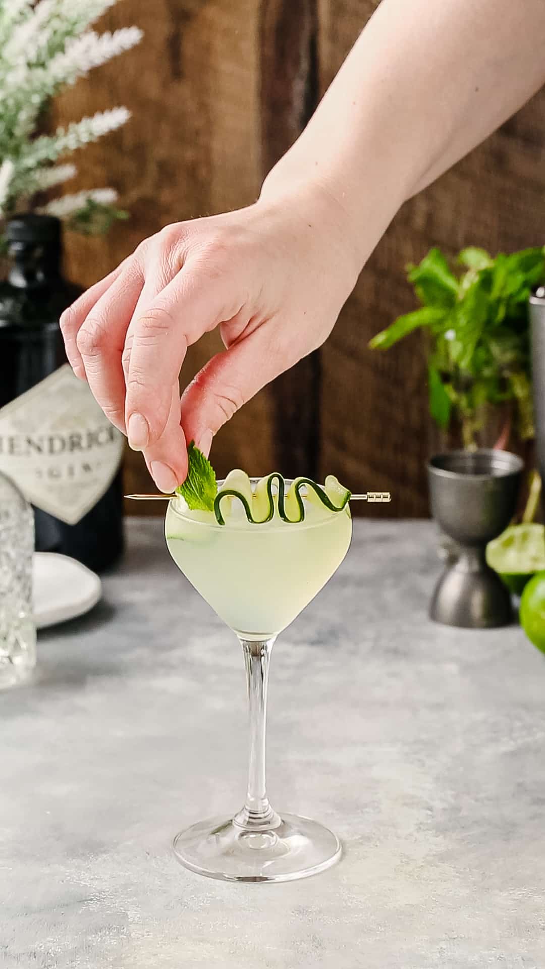 Hand adding a sprig of mint to a cocktail as a garnish.
