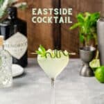 Side view of an Eastside cocktail in a nick and nora cocktail glass with a cucumber and mint garnish, with the text Eastside Cocktail above the drink image.