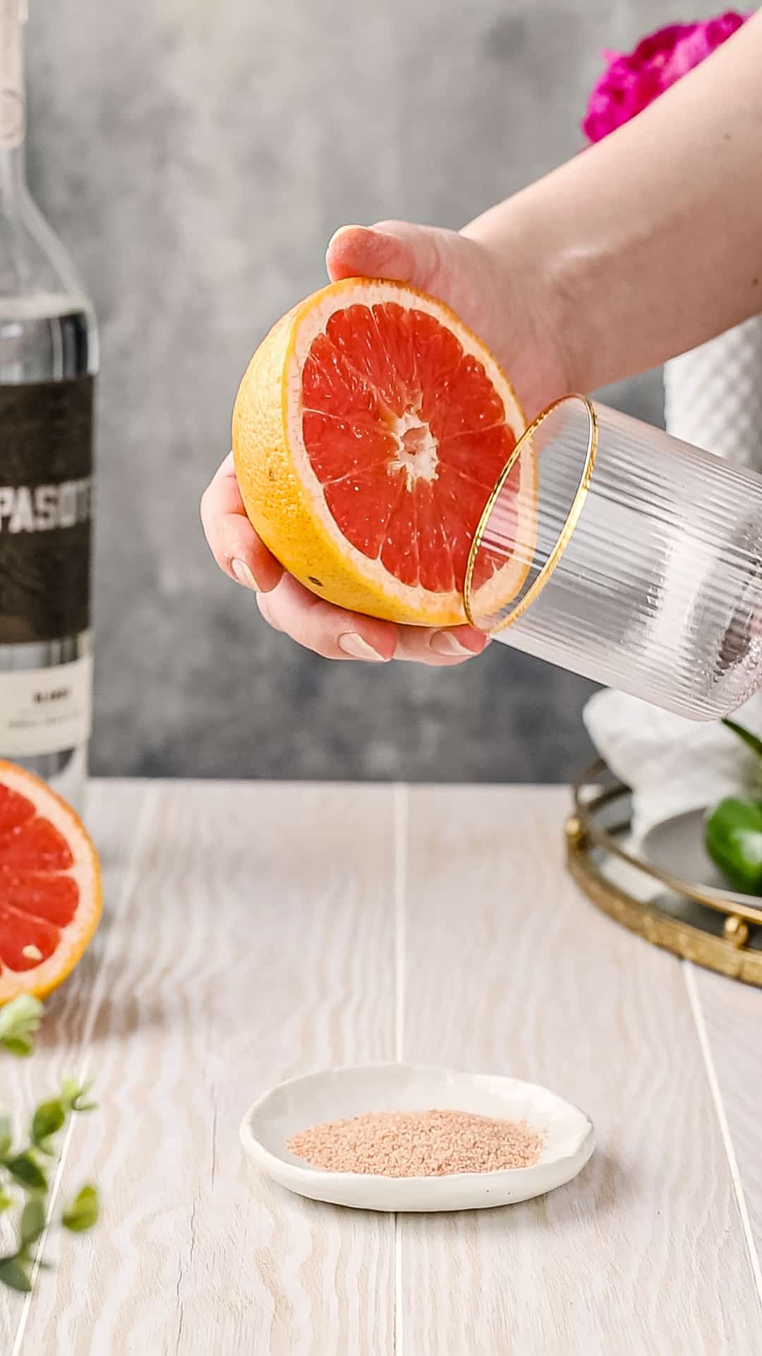 Using a sliced grapefruit to wet the rim of a cocktail glass.