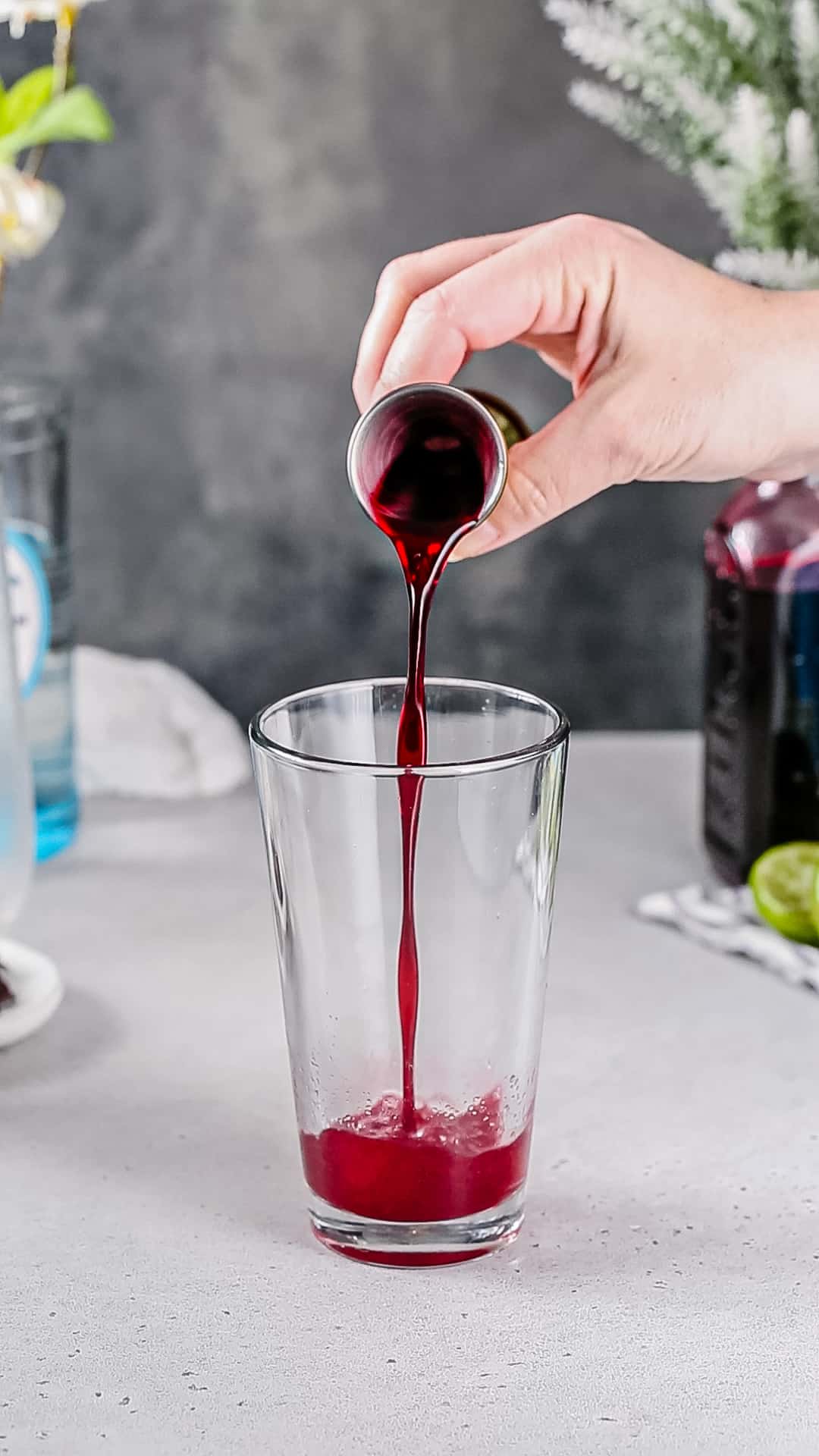 Pouring hibiscus syrup into a cocktail shaker.