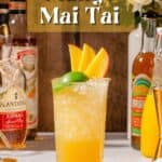 Side view of Mango Mai Tai cocktail with a lime and mango garnish along with ingredients to make it in the background.