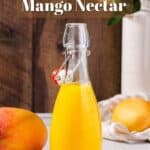 Side view of mango nectar in a glass bottle with mangoes around it and flowers in the background and the text Homemade Mango Nectar above it.
