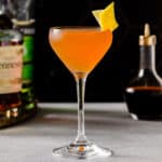 Side view of a Champs-Élysées cocktail with Hennessy Cognac, green Chartreuse liqueur and angostura bitters in the background.