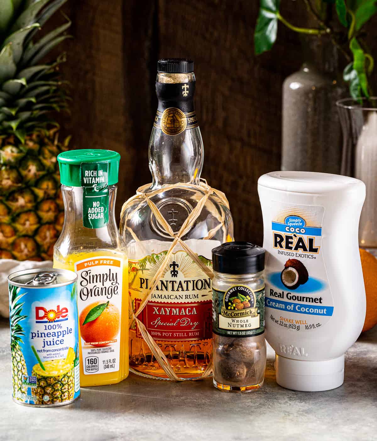 Ingredients for a Painkiller rum cocktail on a countertop.