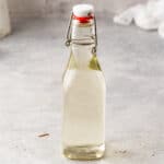 Smoked simple syrup in a swing-top bottle on a gray countertop.
