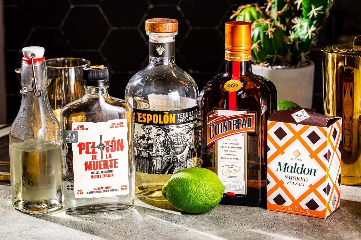 Ingredients to make a Smoky Margarita together on a gray countertop.