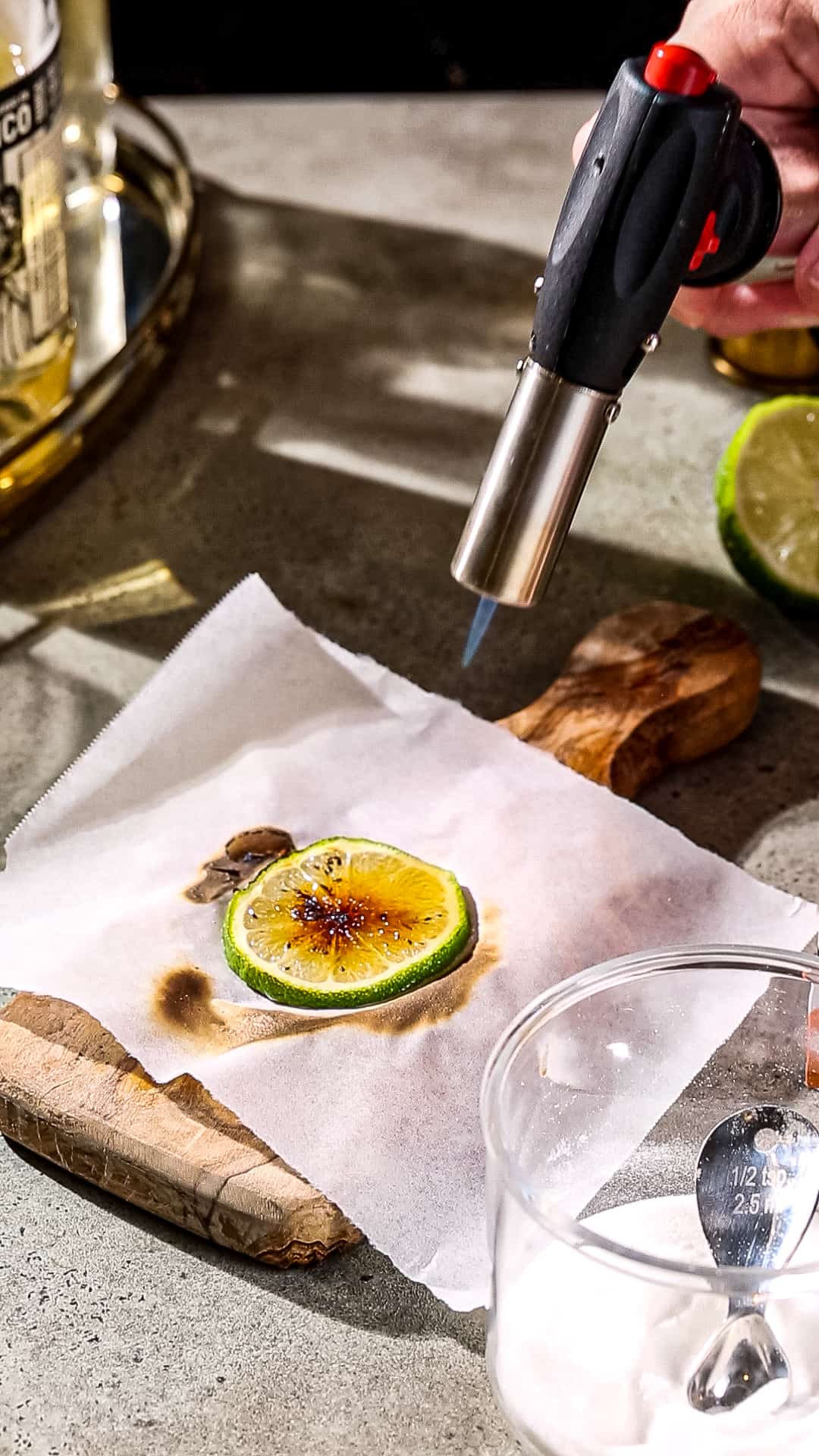 Kitchen torch heating up the sugar on a slice of lime.