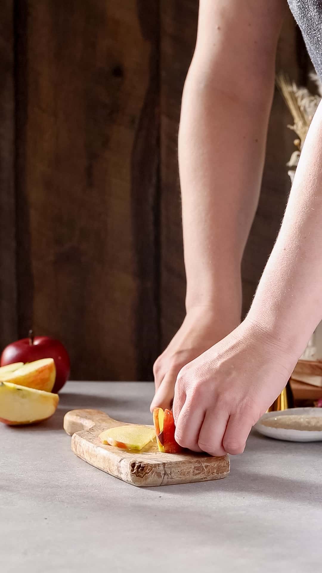 Hands using a knife to cut an apple slice.