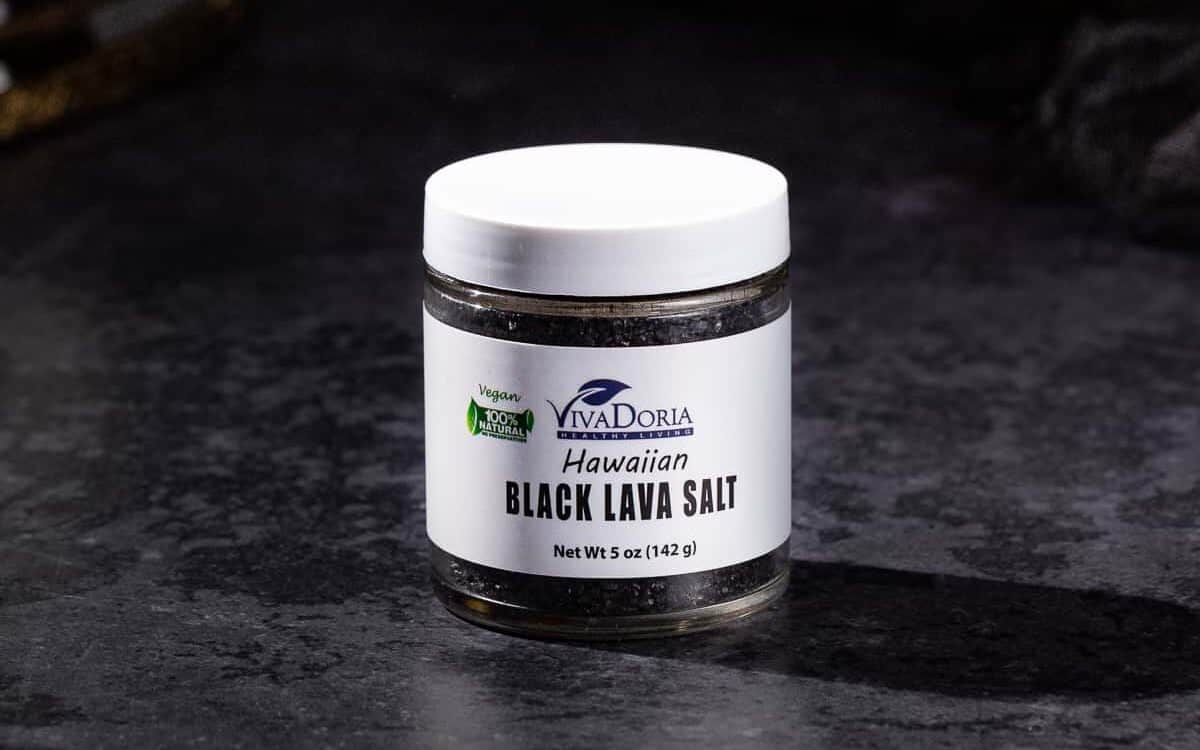 Jar of black lava salt on a dark background.