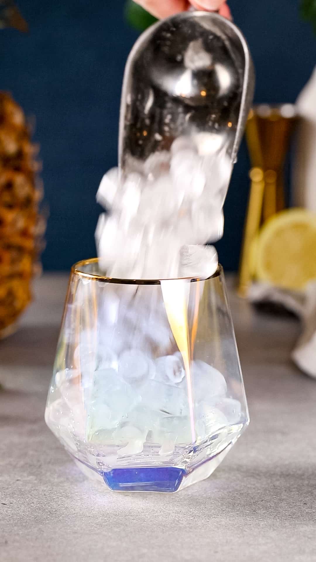 Hand using an ice scoop to add nugget ice to a cocktail glass.